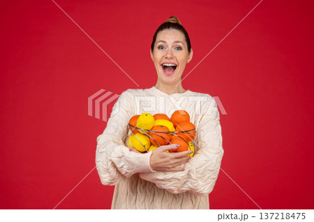 Smiling and happy young woman with fruits in hands 137218475