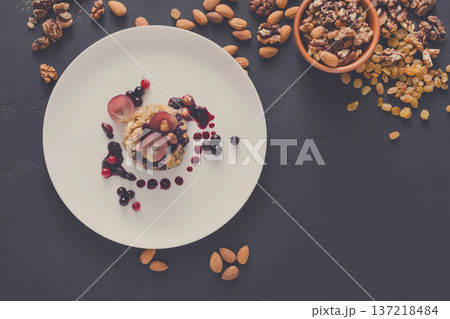 Healthy eating, dieting and detox concept - wholegrain fresh oatmeal porridge on plate with fruits, berries and nuts on dark background. Still life, top view. 137218484