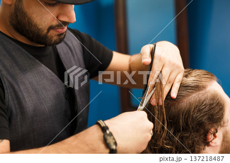 Closeup of making modern hairstyle in male barbershop. Barber and bearded client. Closeup of making modern hairstyle in male barbershop. Barber and bearded client. 137218487