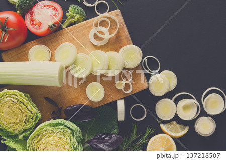 Cooking healthy food background. Cutting leek, fresh organic vegetables on black. Natural food with copy space. Cooking healthy food background. Cutting leek, fresh organic vegetables on black. Natural food with copy space. 137218507