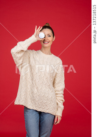 Beautiful young woman on red background with a jar of cream in hand Beautiful young woman on red background with a jar of cream in hand 137218515