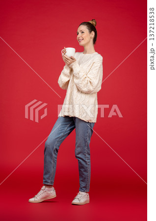 Beautiful young woman on red background with a cup in hand 137218538