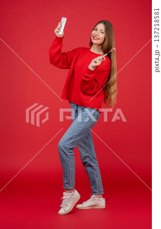 Young pretty woman in red sweater with a facial brush in hands 137218581