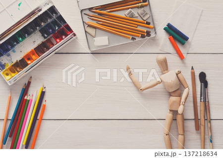 Painting visual art background. Paints and wooden painter man with brushes on white desk, top view, flat lay, objects 137218634