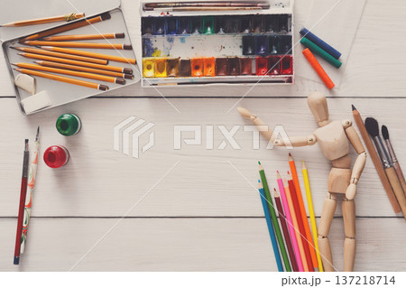 Painting visual art background. Paints and wooden painter man with brushes on white desk, top view, flat lay, objects Painting visual art background. Paints and wooden painter man with brushes on white desk, top view, flat lay, objects 137218714
