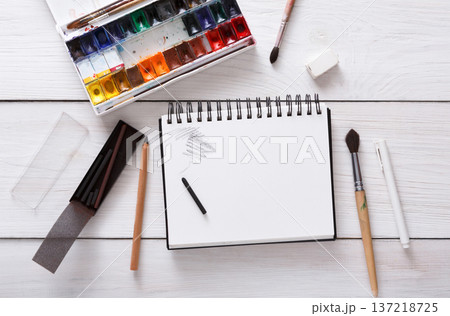 Drawing tools, stationary supplies, workplace of artist. Watercolor paints and blank paper on white wooden desk, top view, flat lay, copy space Drawing tools, stationary supplies, workplace of artist. Watercolor paints and blank paper on white wooden desk, top view, flat lay, copy space 137218725