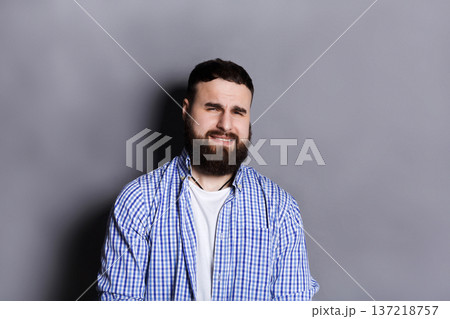 Bearded man expressing disgust on face, grimacing on camera, gray studio background. Negative emotions Bearded man expressing disgust on face, grimacing on camera, gray studio background. Negative emotions 137218757