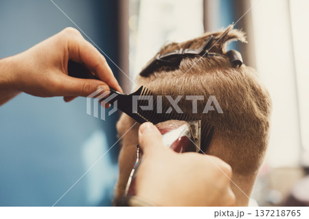 Barber make haircut with hair clipper in barbershop, closeup of client's head. Stylish hairdresser in male hair salon Barber make haircut with hair clipper in barbershop, closeup of client's head. Stylish hairdresser in male hair salon 137218765