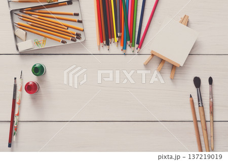 Artist workspace. Drawing tools, stationary supplies, workplace of artist. Watercolor paints and blank paper on white wooden desk, top view, flat lay, copy space Artist workspace. Drawing tools, stationary supplies, workplace of artist. Watercolor paints and blank paper on white wooden desk, top view, flat lay, copy space 137219019