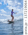 Energetic Woman Confidently Surfs Across Sunlit Blue Waters With Enthusiasm 137219064