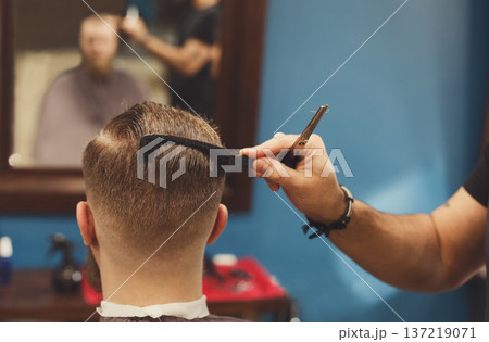 Barber make haircut with scissors in barbershop, closeup of client's head. Hairstyle in male hair salon 137219071