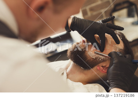 Barber in barbershop make beard haircut, shaving, closeup. Hairstyle in male hair salon 137219186