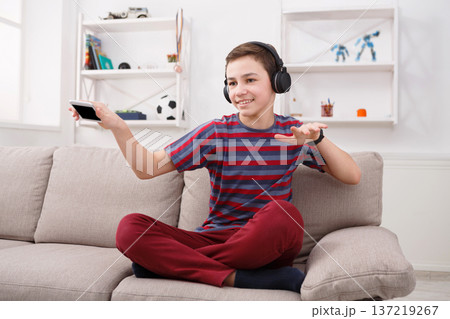 Joyful teenage boy enjoying music in headphones at home. Relax time 137219267