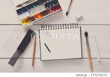 Drawing tools, stationary supplies, workplace of artist. Watercolor paints and blank paper on white wooden desk, top view, flat lay, copy space Drawing tools, stationary supplies, workplace of artist. Watercolor paints and blank paper on white wooden desk, top view, flat lay, copy space 137219272