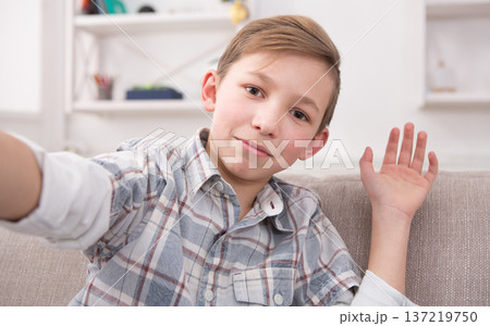Happy child making selfie for social networks. Boy at home on sofa in living room Happy child making selfie for social networks. Boy at home on sofa in living room 137219750