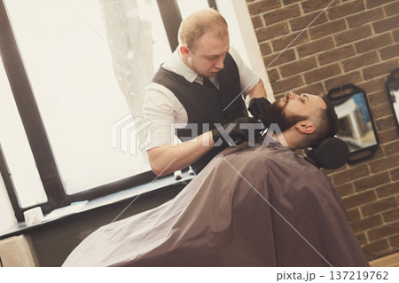 Barber styling beard with trimmer at barbershop, closeup. Hairdressing salon for men 137219762