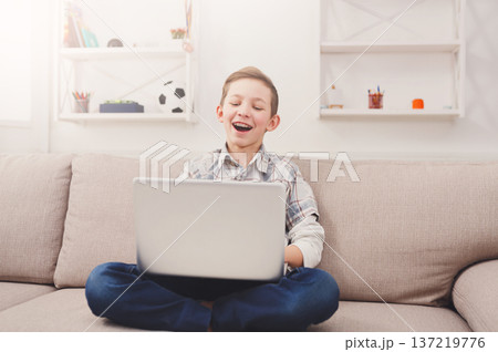 Boy has fun with computer at home. Children and internet, modern technology concept Boy has fun with computer at home. Children and internet, modern technology concept 137219776