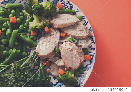 Healthy food, diet nutrition. Green steamed vegetables and slices of chicken on bright geometric background, top view, copy space 137219942