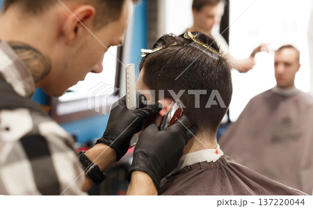 Barber making male haircut in barbershop, closeup. Getting hipster hairstyle in hair salon Barber making male haircut in barbershop, closeup. Getting hipster hairstyle in hair salon 137220044