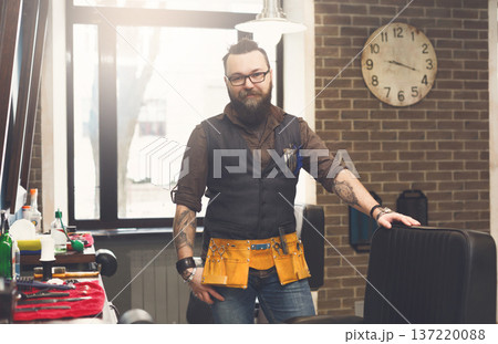 Experienced bearded barber at workplace in barbershop. Professional stylish hairdresser waiting for client at hair salon 137220088