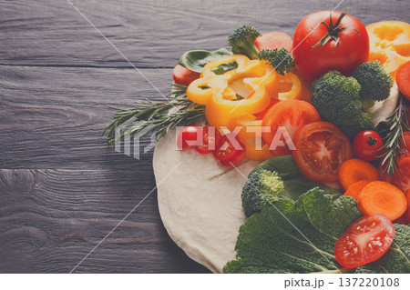 Cooking healthy vegetarian food on dark wooden background. Fresh organic vegetables on pita flatbread. Natural food with copy space. Cooking healthy vegetarian food on dark wooden background. Fresh organic vegetables on pita flatbread. Natural food with copy space. 137220108