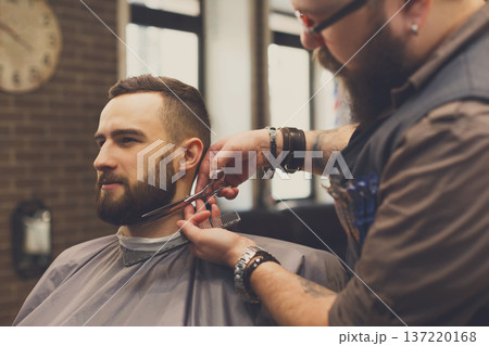 Barber styling beard with scissors at barbershop. Stylish hairdresser in male hair salon Barber styling beard with scissors at barbershop. Stylish hairdresser in male hair salon 137220168