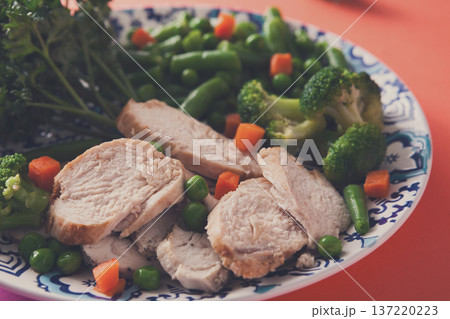 Healthy food, diet nutrition. Green steamed vegetables and slices of chicken fillet on bright geometric background, closeup, copy space Healthy food, diet nutrition. Green steamed vegetables and slices of chicken fillet on bright geometric background, closeup, copy space 137220223