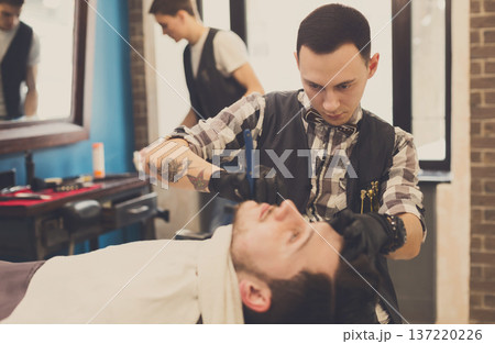 Barber styling beard with trimmer at barbershop, closeup. Barbershop for men Barber styling beard with trimmer at barbershop, closeup. Barbershop for men 137220226