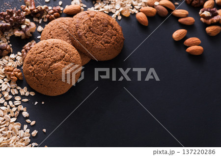 Healthy oat cookies made of wholegrain oat and nuts on dark table background, free copy space. Flat lay, mockup, template, objects, nobody 137220286