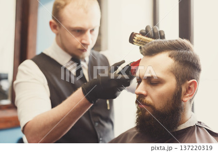 Man getting haircut by hairstylist at barbershop. Stylish barber and client Man getting haircut by hairstylist at barbershop. Stylish barber and client 137220319