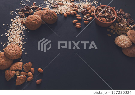 Healthy organic oat cookies made of wholegrain oat and nuts on dark table background, free copy space. Flat lay, mockup, template, objects, nobody Healthy organic oat cookies made of wholegrain oat and nuts on dark table background, free copy space. Flat lay, mockup, template, objects, nobody 137220324