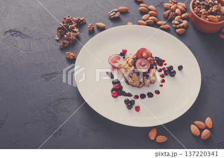 Healthy eating, dieting and detox concept - wholegrain fresh oatmeal porridge with fruits, berries and nuts on dark background. Healthy eating, dieting and detox concept - wholegrain fresh oatmeal porridge with fruits, berries and nuts on dark background. 137220341