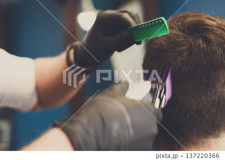 Barber make haircut with hair clipper in barbershop, closeup of client's head. Stylish hairdresser in male hair salon Barber make haircut with hair clipper in barbershop, closeup of client's head. Stylish hairdresser in male hair salon 137220366
