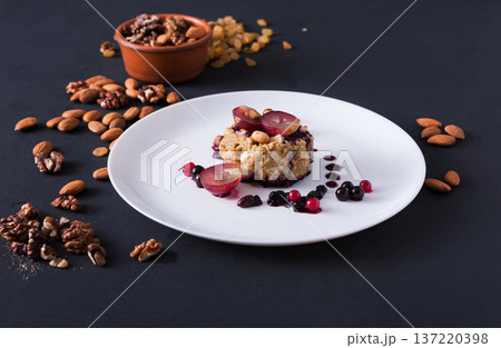 Healthy eating, dieting and detox concept - wholegrain fresh oatmeal porridge with fruits, berries and nuts on dark background. Healthy eating, dieting and detox concept - wholegrain fresh oatmeal porridge with fruits, berries and nuts on dark background. 137220398