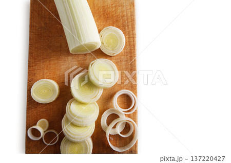Cooking healthy food. Sliced and chopped leek on wooden cutting board isolated at white background Cooking healthy food. Sliced and chopped leek on wooden cutting board isolated at white background 137220427