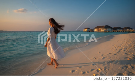 夕暮れのモルディブの海辺を歩く女性と水上ヴィラ 137221030