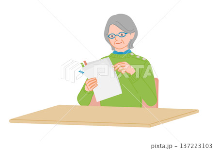 付箋付き書類を確認するシニア女性 屋内の机で読む日本人高齢者 137223103