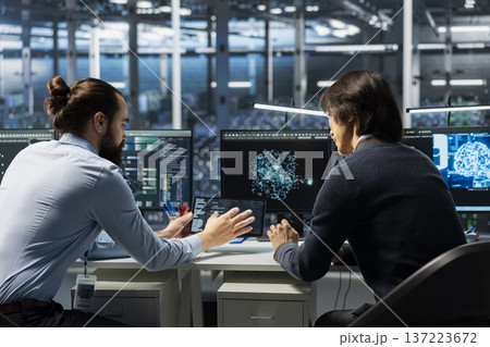 Technicians in data center installing upgraded server racks systems helped by AI technology. Server hub workers upgrading enterprise networks hardware using artificial intelligence Technicians in data center installing upgraded server racks systems helped by AI technology. Server hub workers upgrading enterprise networks hardware using artificial intelligence 137223672