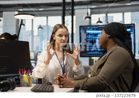 Junior dev and female programmer gossiping about coworkers, having fun. Group of women engaged in workplace chat during job shift break, exchanging office news about colleagues 137223679