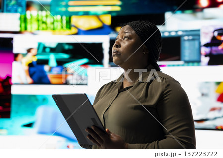 Woman using device to look at social media feed mapping global entertainment content. Person surrounded by floating icons uses and interactive digital interface on tablet to do social media engagement 137223722