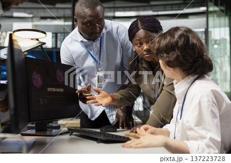 Startup office programmer doing software debugging, helped by coworkers to fix malware. IT worker fighting hacker ddos attack, being assisted by team members sharing helpful advice 137223728
