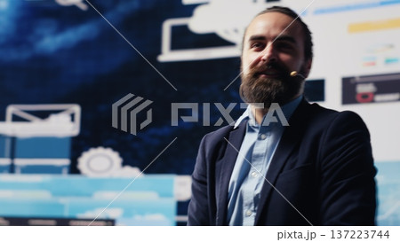 Male entrepreneur leading a visionary business pitch at the convention, inspiring the audience to fund important project. Businessman public speaker giving a speech for the crowd. Camera A. 137223744