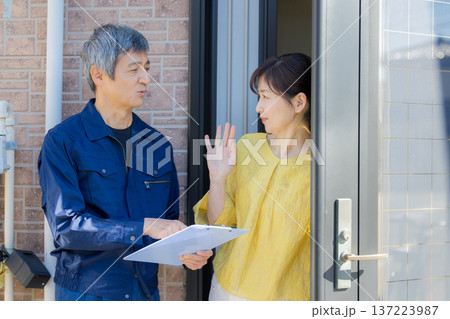 玄関で説明する作業服の男性 137223987
