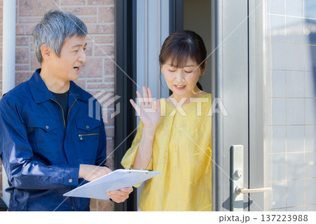 玄関で説明する作業服の男性 137223988