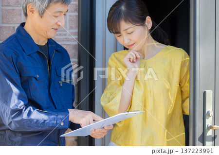 玄関で説明する作業服の男性 137223991