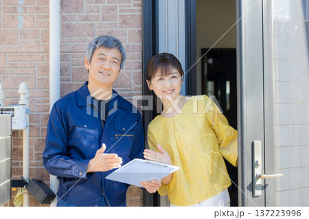 玄関で説明する作業服の男性 137223996