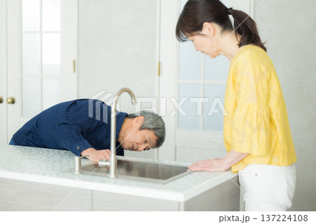 水回りの説明をする作業服の男性 137224108