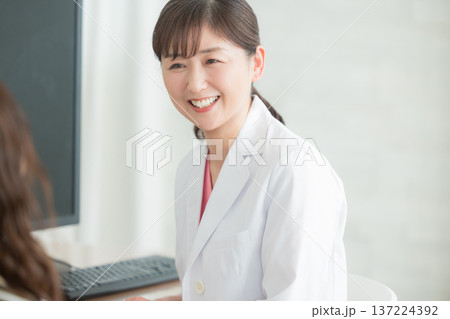 患者に説明する白衣の女性 患者に説明する白衣の女性 137224392