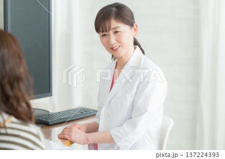患者に説明する白衣の女性 患者に説明する白衣の女性 137224393