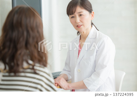 患者に説明する白衣の女性 患者に説明する白衣の女性 137224395